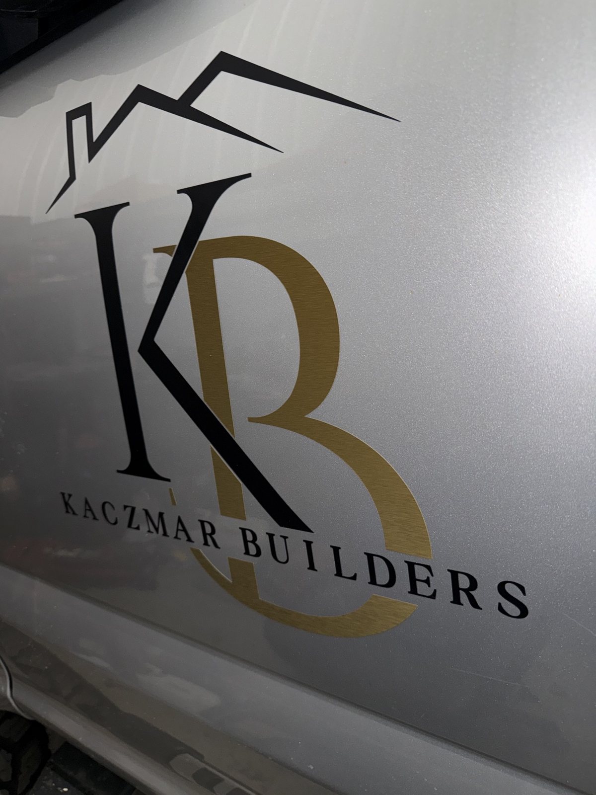 Close-up of the Kaczmar Builders logo graphic on the wrapped F-250 door
