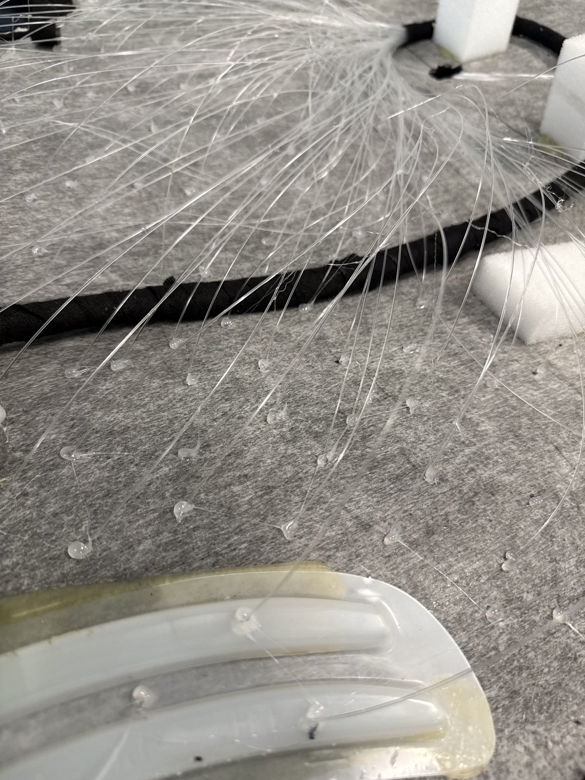 Close-up of fiber-optic strands being placed by hand into a headliner