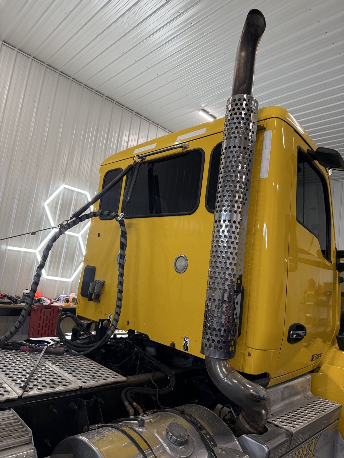 Yellow Kenworth T680 semi cab in the shop with tinted sleeper and side windows