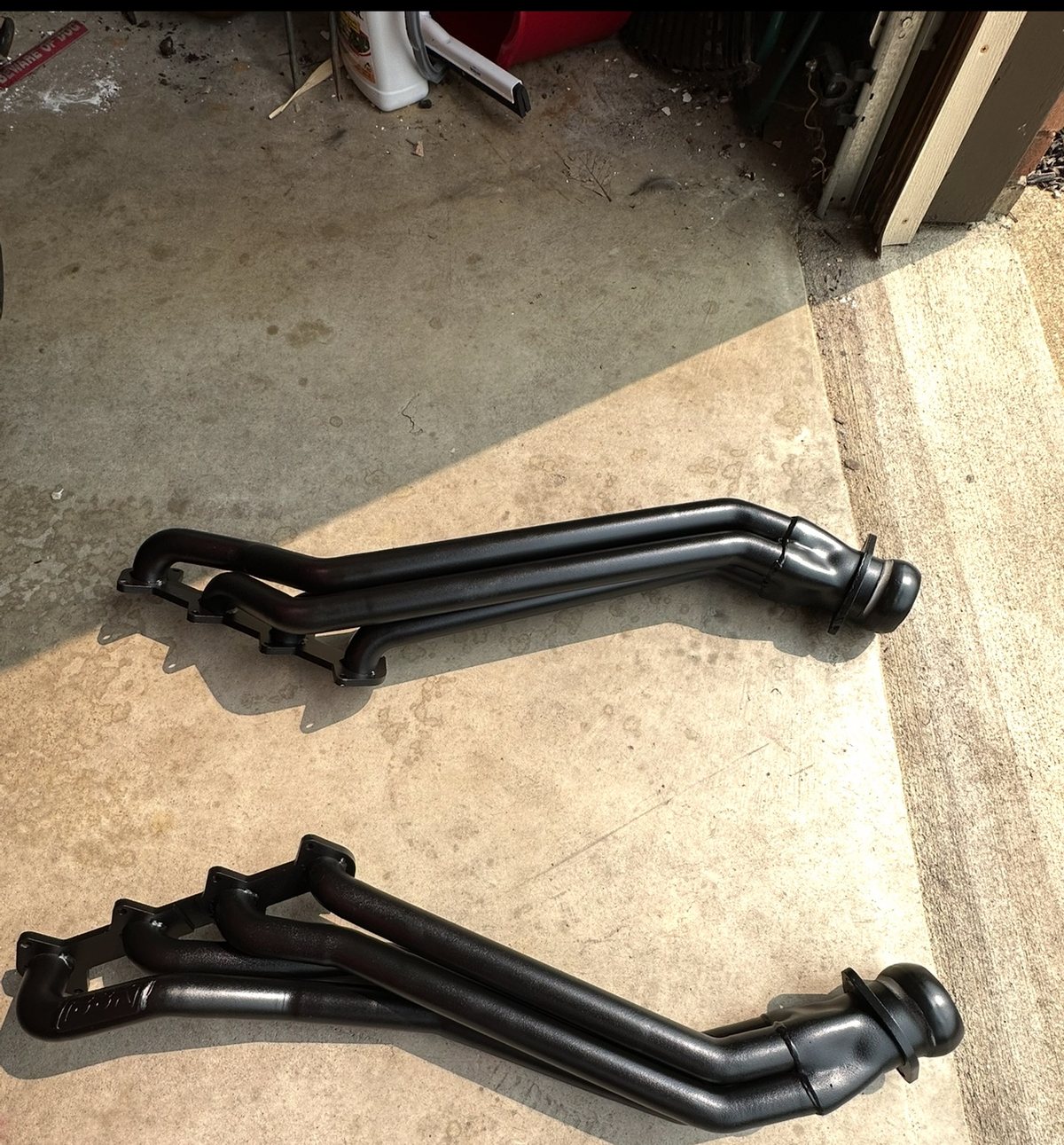 Black long-tube headers laid out on the shop floor, ready to install