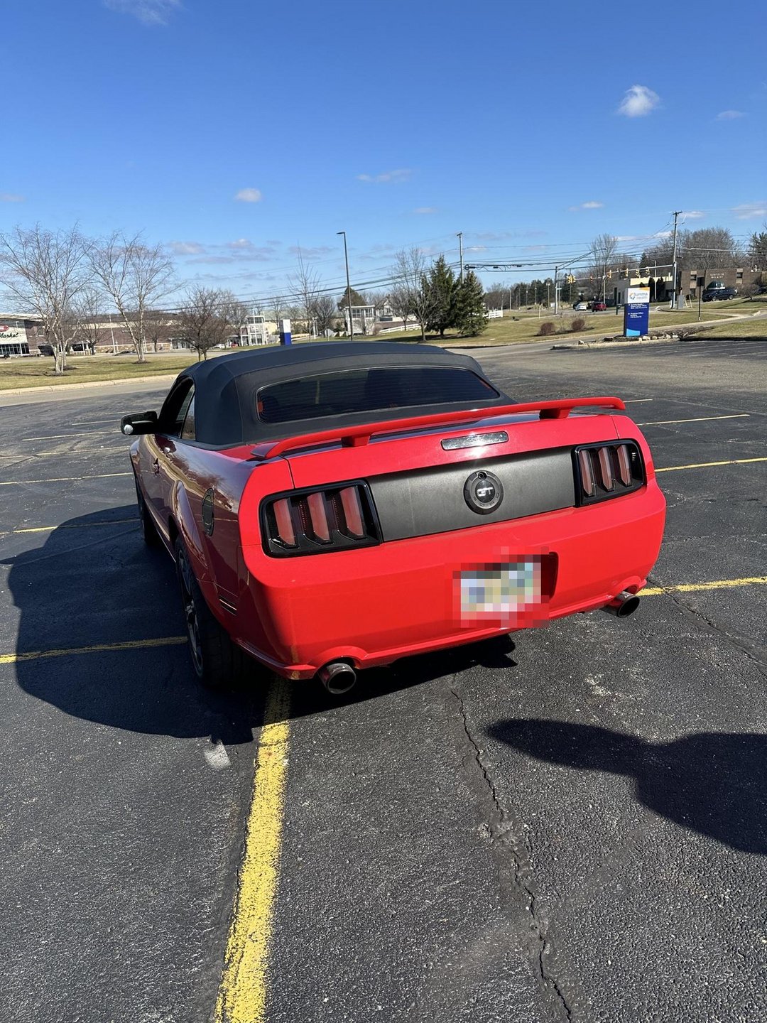 Past shop build — red 2006 Mustang GT convertible rear three-quarter view with custom taillights; license plate blurred