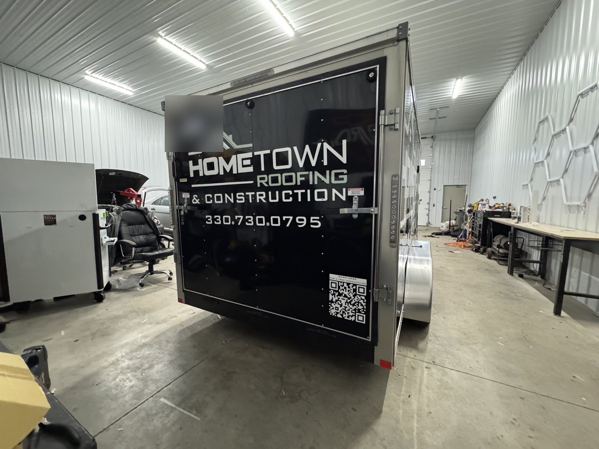 Rear of the wrapped Hometown Roofing enclosed trailer inside the 1Stop shop