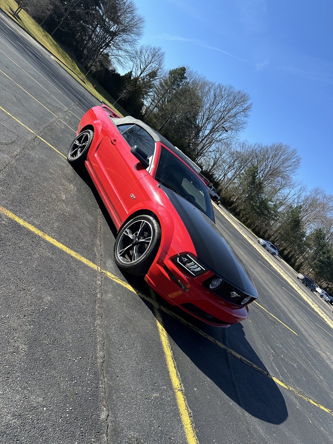 Past shop build — red 2006 Mustang GT convertible front three-quarter view with black hood wrap, parked outdoors