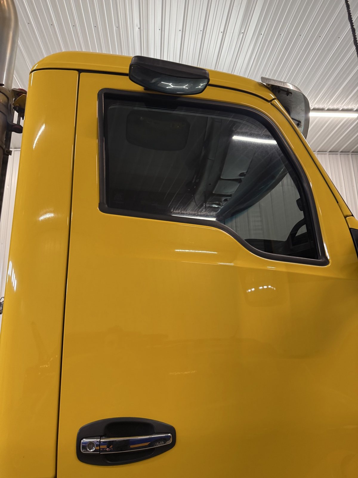 Close-up of the yellow Kenworth cab door with freshly tinted driver window