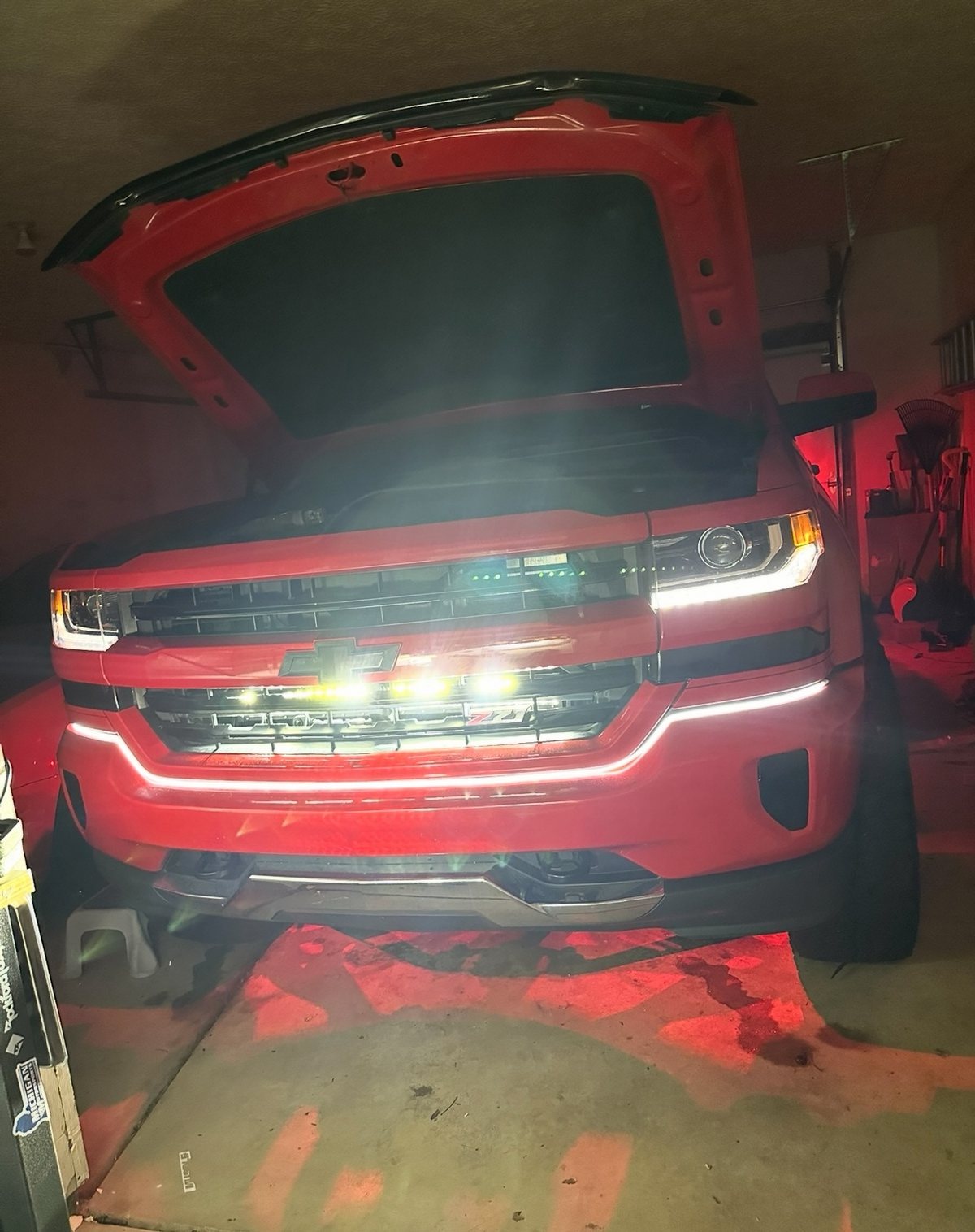 Red Silverado front end with the behind-grille light bar lit and hood open