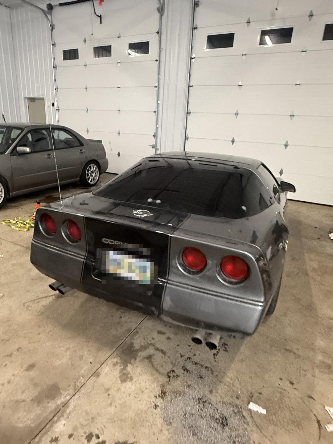 Past shop build — grey 1985 Corvette rear view inside the shop; license plate blurred