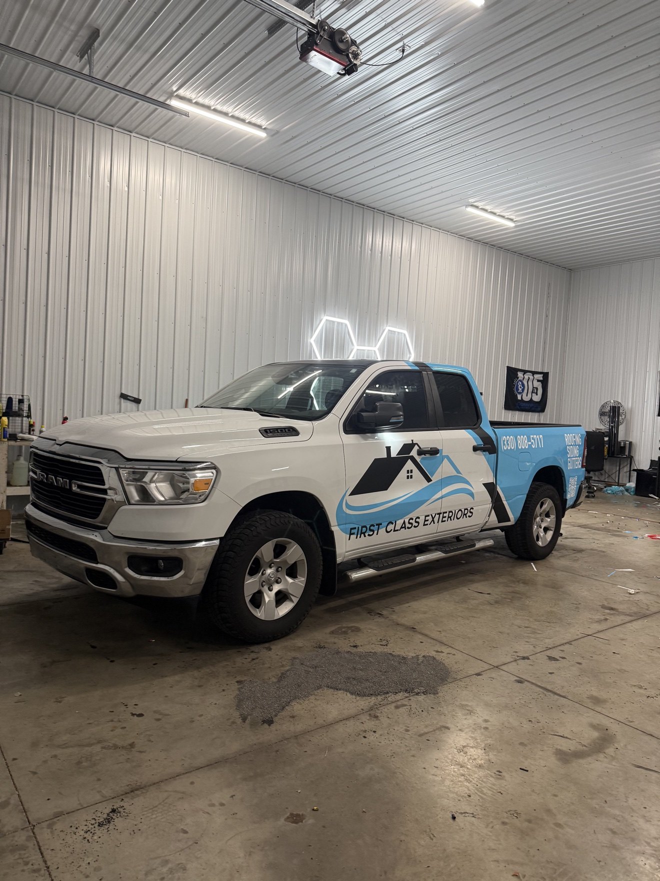 First Class Exteriors Ram 1500 pickup with its finished full commercial wrap, parked inside the 1Stop Auto Performance shop