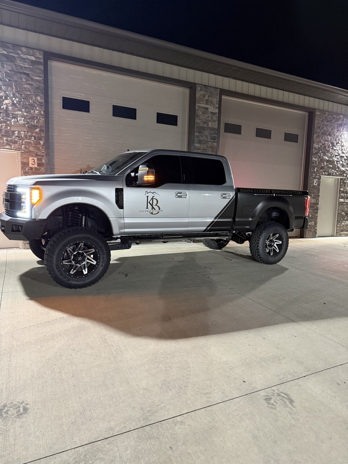 Kaczmar Builders Ford F-250 with satin black and gold graphics, full side profile at night