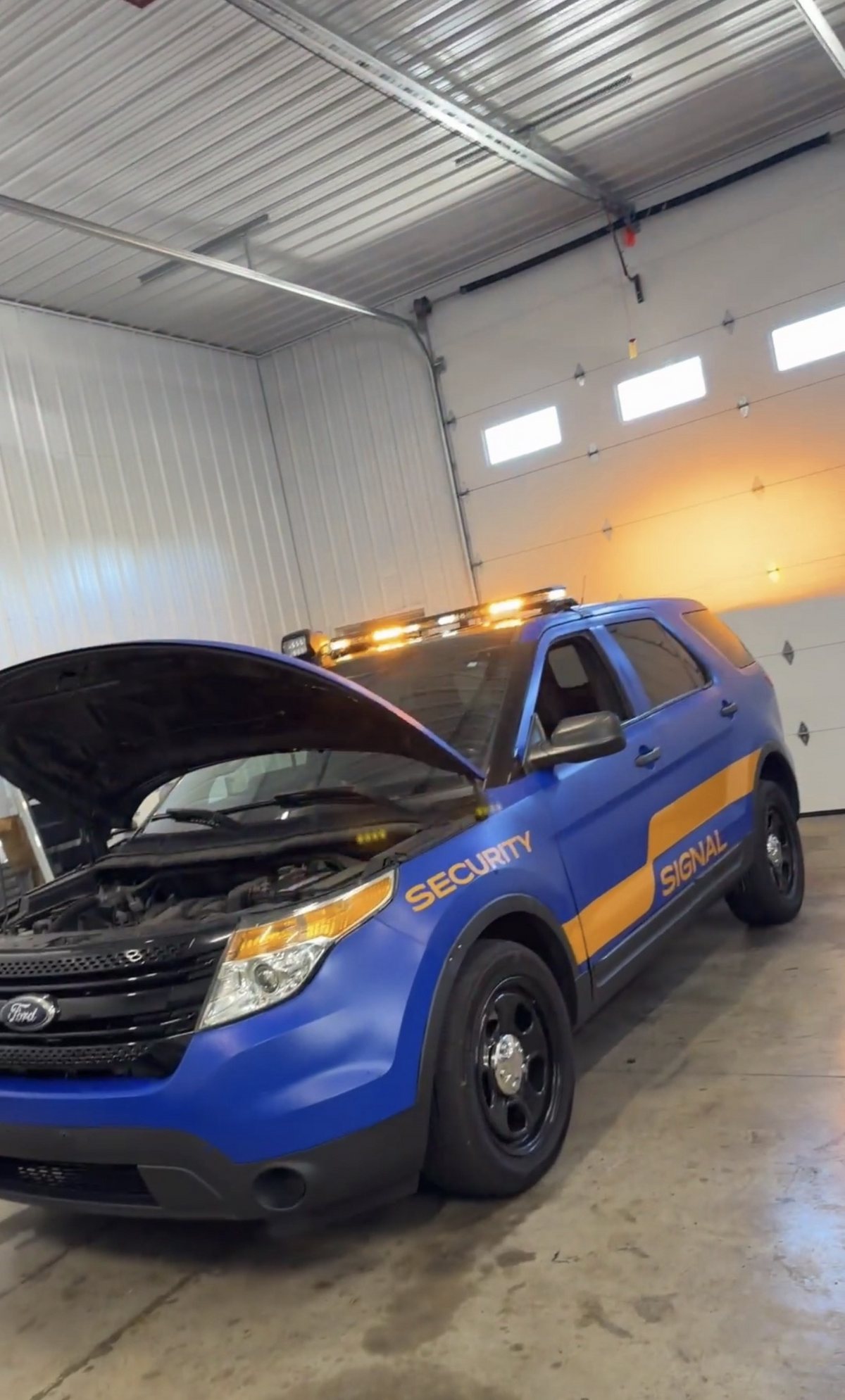 Signal Security Ford Explorer in the shop with its hood open during the light bar upfit