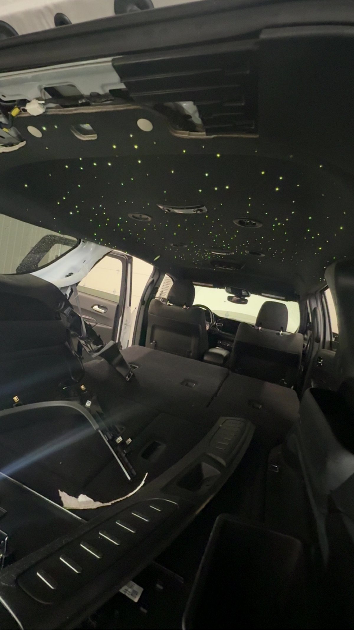 Finished starlight headliner glowing green and white inside an SUV