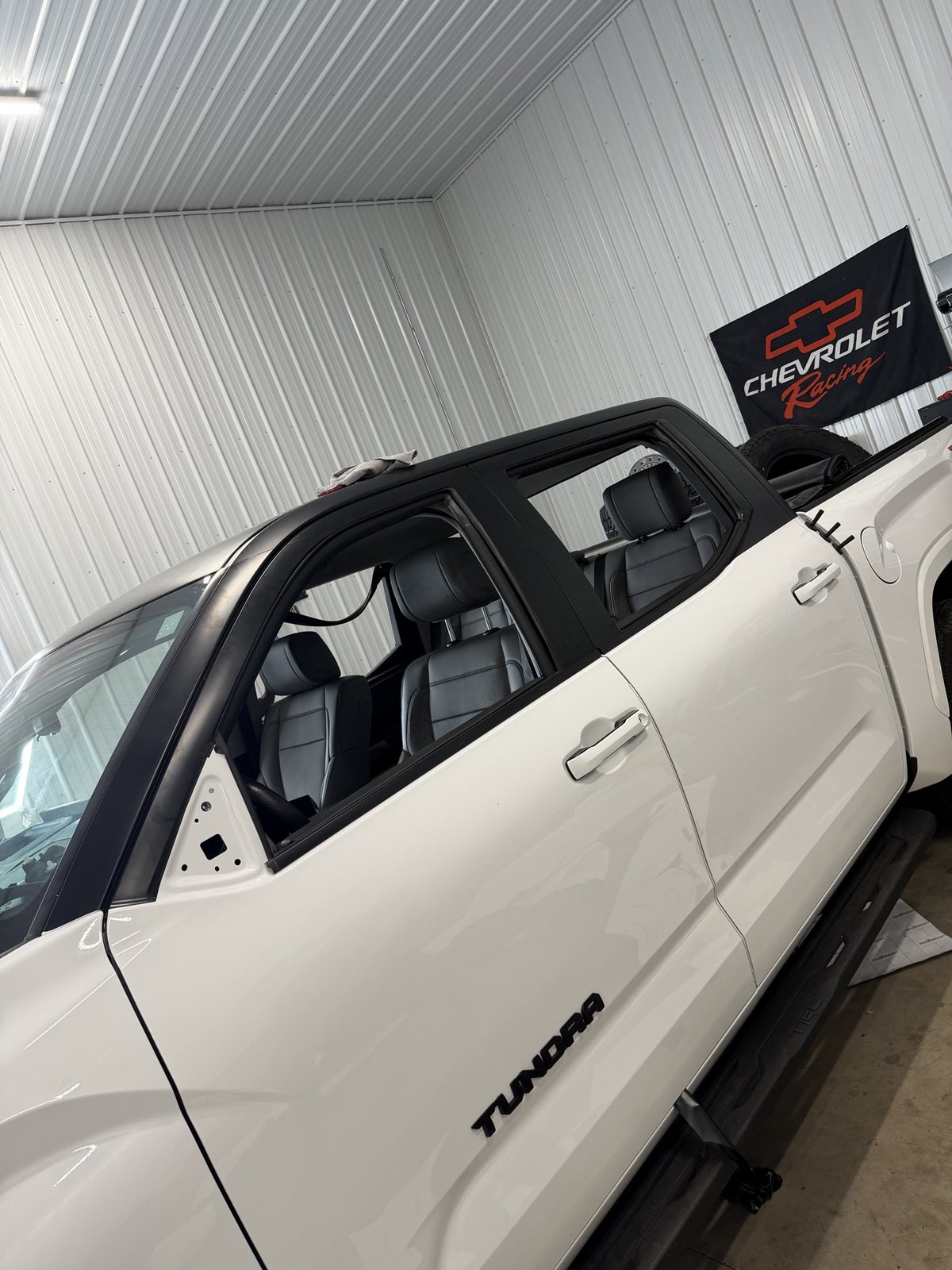 Toyota Tundra in the shop mid-wrap, black roof and pillars going on, mirror removed