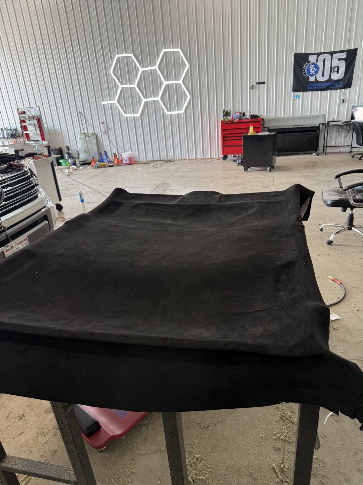 Black suede headliner material laid out on a table in the shop