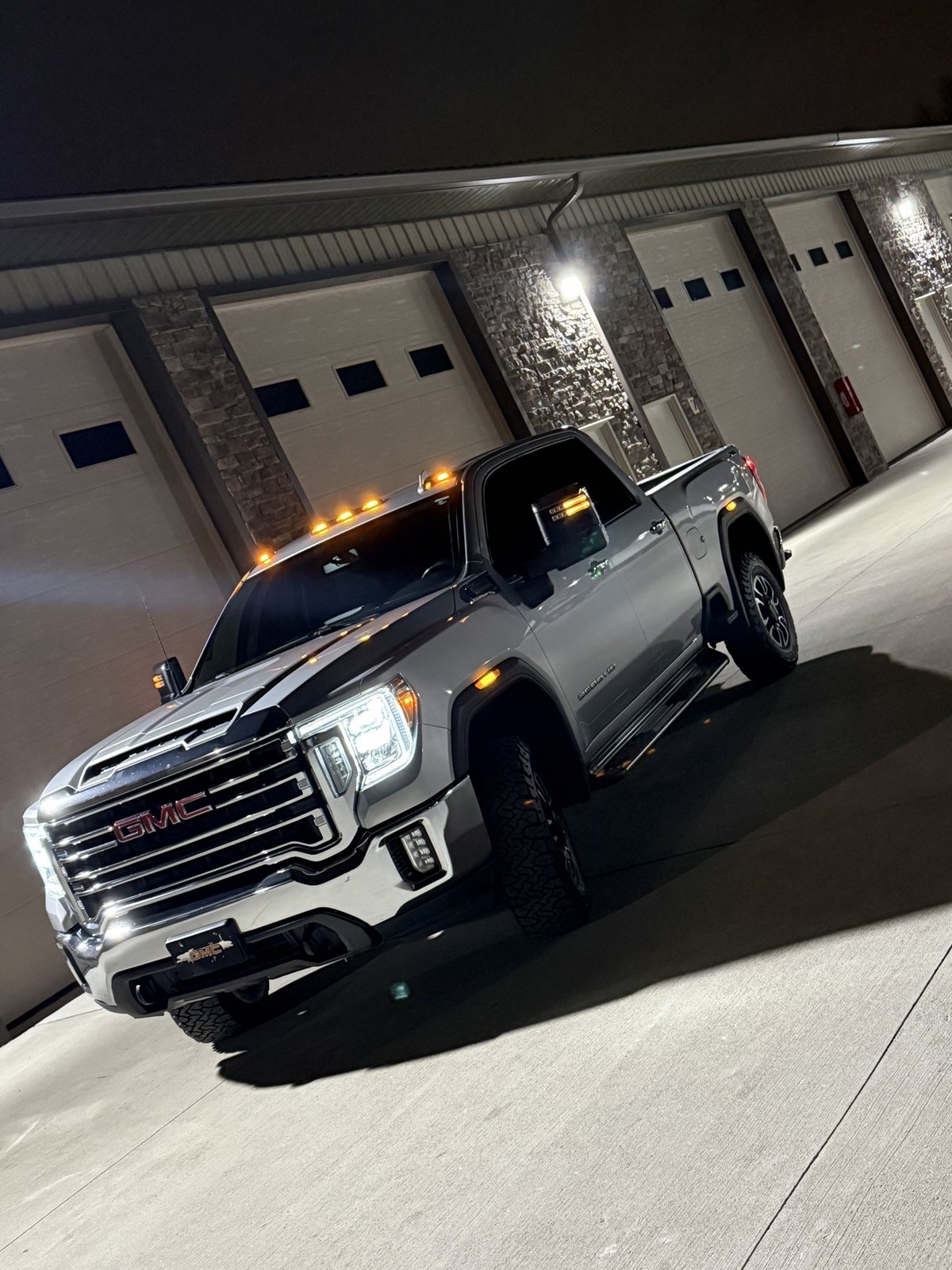 Owner's silver 2020 GMC Sierra 2500HD Duramax at night, LED headlights and amber cab markers lit