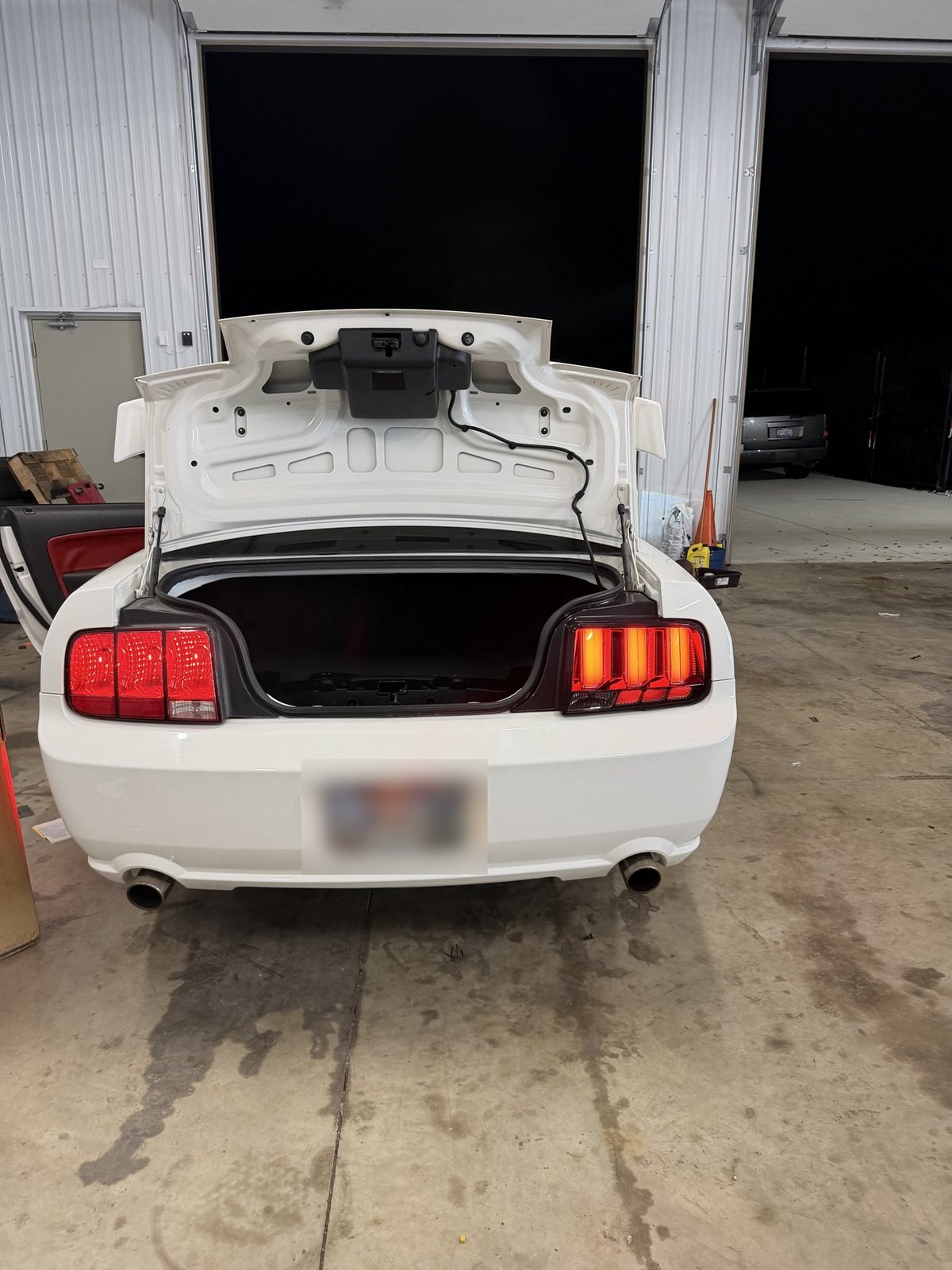 White Mustang GT rear view with trunk open and its LED taillights lit