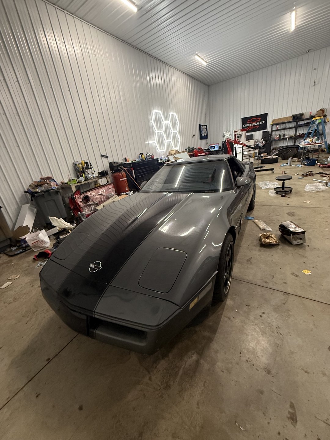 Past shop build — grey 1985 Corvette front three-quarter view inside the shop